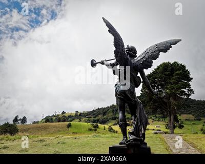 Eine monumentale Engelskulptur mit einer Trompete vor einer üppigen grünen Kulisse Stockfoto