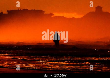 Isle Of Palms, Usa. Juni 2024. Eine Frau steht im Wasser und beobachtet den Sonnenaufgang an einem nebeligen Morgen entlang der Low Country Region, am 3. Juni 2024 in Isle of Palms, South Carolina. Quelle: Richard Ellis/Richard Ellis/Alamy Live News Stockfoto