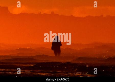 Isle Of Palms, Usa. Juni 2024. Eine Frau steht im Wasser und beobachtet den Sonnenaufgang an einem nebeligen Morgen entlang der Low Country Region, am 3. Juni 2024 in Isle of Palms, South Carolina. Quelle: Richard Ellis/Richard Ellis/Alamy Live News Stockfoto