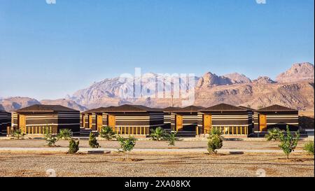 Eine Reihe von Häusern auf unbefestigtem Boden mit fernen Bergen in Wadi Rum, Jordanien Stockfoto