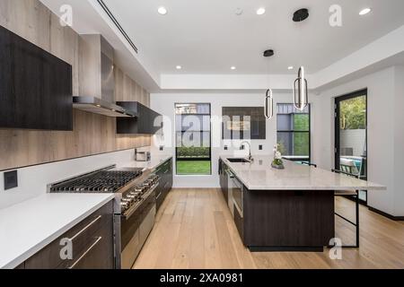 Moderne Küche mit dunklen Schränken, weißen Arbeitsflächen und Holzfußboden Stockfoto