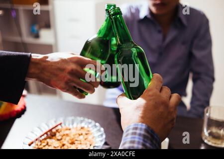 Eine Gruppe von Geschäftsleuten hält Bierflaschen und klirrt einander an, um den Erfolg ihres gemeinsamen Unternehmens zu feiern. Die Idee von ​​cele Stockfoto