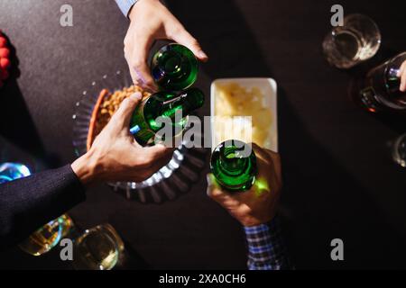 Eine Gruppe von Geschäftsleuten hält Bierflaschen und klirrt einander an, um den Erfolg ihres gemeinsamen Unternehmens zu feiern. Die Idee von ​​cele Stockfoto