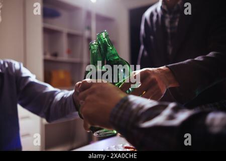 Eine Gruppe von Geschäftsleuten hält Bierflaschen und klirrt einander an, um den Erfolg ihres gemeinsamen Unternehmens zu feiern. Die Idee von ​​cele Stockfoto