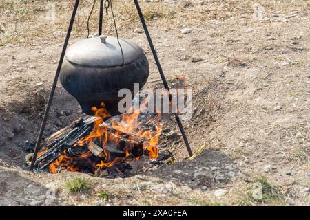 Kochen in altem Gusseisen auf einem Stativ über dem Feuer Stockfoto