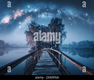 Holzweg und Haus umgeben von Bäumen, Milchstraße-Galaxie Stockfoto