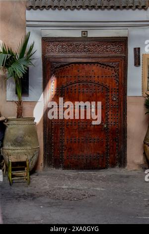 Eine wunderschöne und charmante Ecke von Marrakesch mit einer schönen Holztür mit den typischen Regenschirmnägeln und Bronzeklopfen, um an die Tür zu klopfen Stockfoto