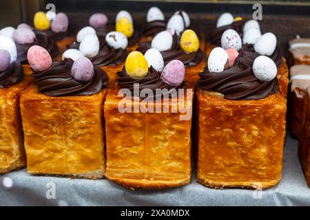 Traditionelle britische Ostergerichte, frisch gebackene gefüllte Brötchen mit Schokolade und dekorative Eier in der Bäckerei Stockfoto