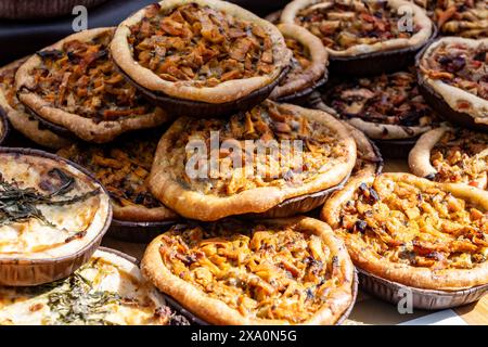 Leckeres vegetarisches Streetfood zum Mittagessen in London, verschiedene Quiche herzhafte Tarte mit Spinat, Tomaten, Pilzen, Cheddar-Käse, Nahaufnahme Stockfoto