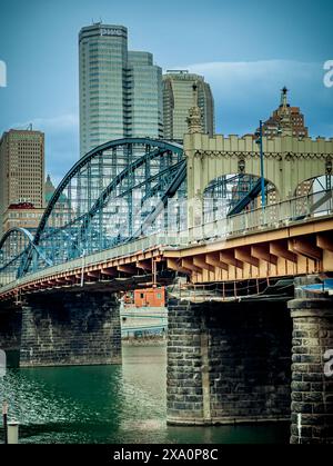 Die Skyline von Pittsburgh mit der Roberto Clemente Bridge über den Allegheny River, mit modernen Glastürmen und historischen Gebäuden unter bewölktem Himmel. Stockfoto