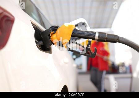 Ein Auto wird an einer Tankstelle mit Benzin gefüllt. Die Gaspumpe ist schwarz und silber Stockfoto