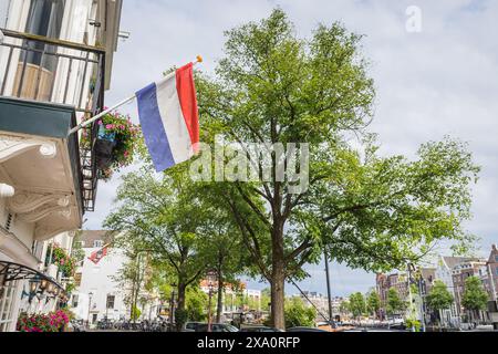 Eine niederländische Flagge über einem Gebäude entlang des Groenburgwal-Kanals in Amsterdam, Niederlande, am 27. Mai 2024. Stockfoto