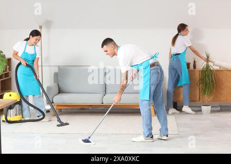 Team junger Hausmeister, die den Boden im Zimmer reinigen Stockfoto