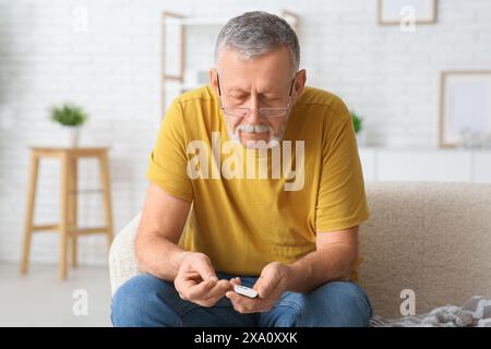 Senior Mann überprüft den Blutzuckerspiegel zu Hause. Diabeteskonzept Stockfoto