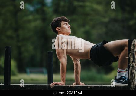 Junger Mann, der im Freien Trizepsdips in einem Naturpark macht Stockfoto