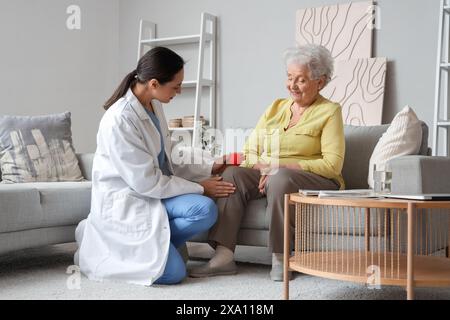 Physiotherapeutin, die zu Hause das Knie einer älteren Frau mit Ball massiert Stockfoto