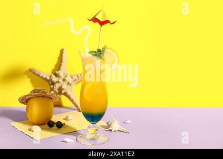 Ein Glas leckerer Cocktail mit Zitrone, Muscheln und Seesternen auf farbenfrohem Hintergrund Stockfoto