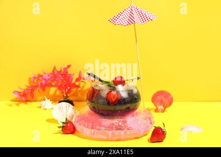 Glas leckerer Cocktail mit Erdbeere, Muscheln, Regenschirm und aufblasbarem Ring auf bunter Hintergrund Stockfoto