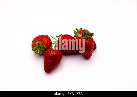 Vier Erdbeeren in einer Reihe auf einer weißen Oberfläche angeordnet Stockfoto
