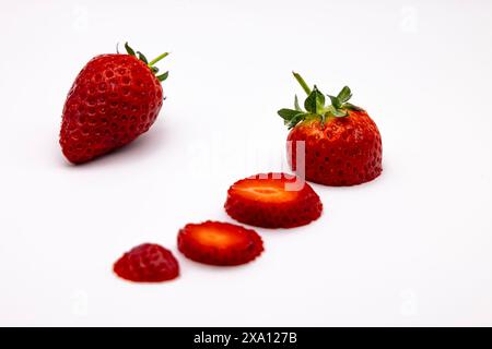 Frisch geschnittene Erdbeeren auf weißem Hintergrund mit leuchtenden Rottönen Stockfoto
