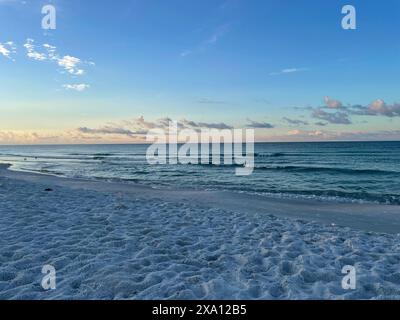 Ein Sandstrand mit ruhigen Meereswellen in der Abenddämmerung Stockfoto