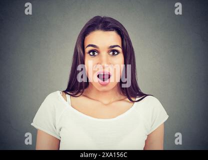 Überraschen Sie die überraschende Frau. Nahaufnahme Porträt Frau, die in voller Unglaublichkeit überrascht blickt, breiter offener Mund isolierter grauer Wandhintergrund. Stockfoto
