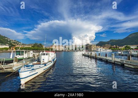 Ein langes Dock voller zahlreicher weißer Boote vor einer bergigen Kulisse in Como, Italien Stockfoto