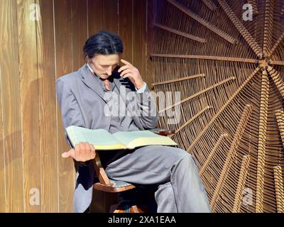 Eine Person, die auf einem Tisch sitzt und mit einem Buch im Nikola Tesla Museum in Belgrad, Serbien, Multitasking macht Stockfoto