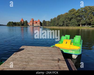 Einige grüne und gelbe Tretboote im Trakai-See mit Trakai-Burg im Hintergrund, in Litauen Stockfoto