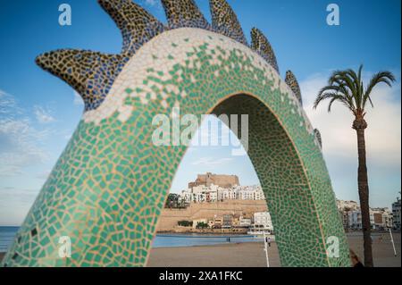 Blick auf das Schloss Papa Luna durch die Drachenskulptur an der Strandpromenade in Peñiscola, Castellon, Valencianische Gemeinde, Spanien Stockfoto