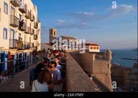 Besucher genießen den Sonnenuntergang von einem Restaurant an den Stadtmauern des Schlosses Papa Luna in Peñiscola, Castellon, Valencianische Gemeinde, Spanien Stockfoto