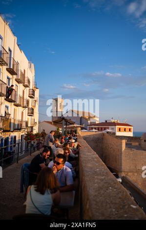 Besucher genießen den Sonnenuntergang von einem Restaurant an den Stadtmauern des Schlosses Papa Luna in Peñiscola, Castellon, Valencianische Gemeinde, Spanien Stockfoto