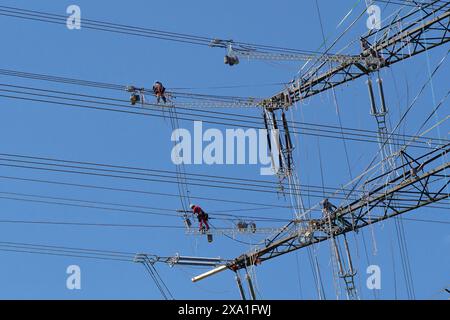 Ein Team von Arbeitern an einem Hochspannungsmast, die Kabel reparieren. Deutschland Stockfoto