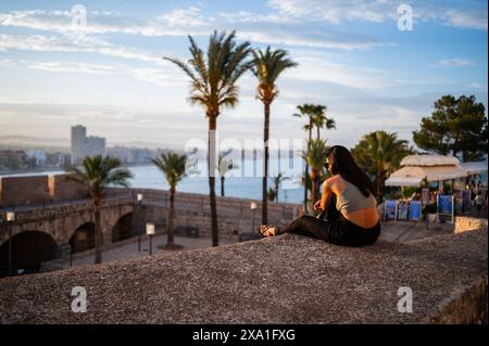 Junge Frau, die den Sonnenuntergang von den Stadtmauern des Schlosses Papa Luna in Peñiscola, Castellon, Valencianische Gemeinde, Spanien genießt Stockfoto