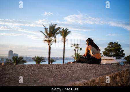 Junge Frau, die den Sonnenuntergang von den Stadtmauern des Schlosses Papa Luna in Peñiscola, Castellon, Valencianische Gemeinde, Spanien genießt Stockfoto