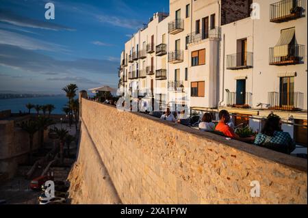 Besucher genießen den Sonnenuntergang von einem Restaurant an den Stadtmauern des Schlosses Papa Luna in Peñiscola, Castellon, Valencianische Gemeinde, Spanien Stockfoto