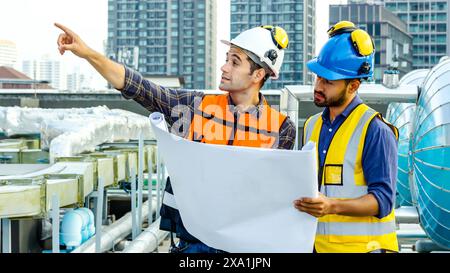 Die beiden Männer prüfen Baupläne für Baumaterialien auf einem Dach. Stockfoto