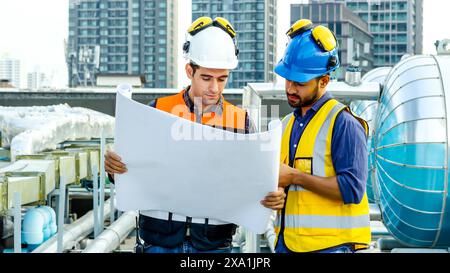 Die beiden Männer prüfen Baupläne für Baumaterialien auf einem Dach. Stockfoto