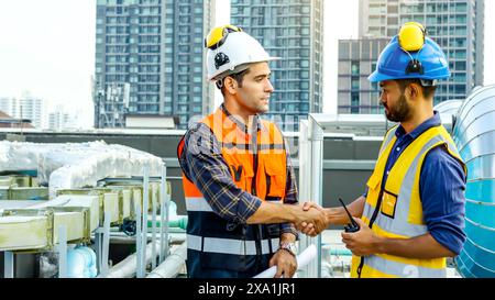 Die beiden Bauarbeiter diskutieren und schütteln die Hand über die Baupläne. Stockfoto