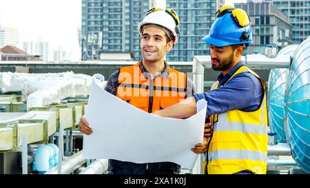 Die beiden Männer prüfen Baupläne für Baumaterialien auf einem Dach. Stockfoto