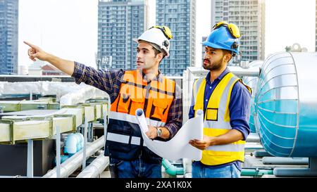 Die beiden Männer prüfen Baupläne für Baumaterialien auf einem Dach. Stockfoto