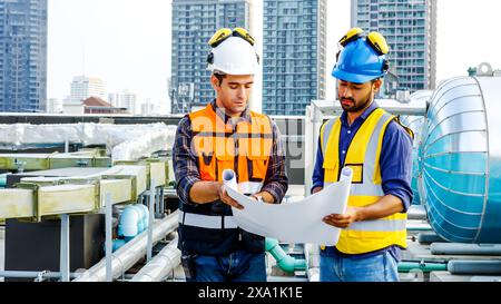 Die beiden Männer prüfen Baupläne für Baumaterialien auf einem Dach. Stockfoto