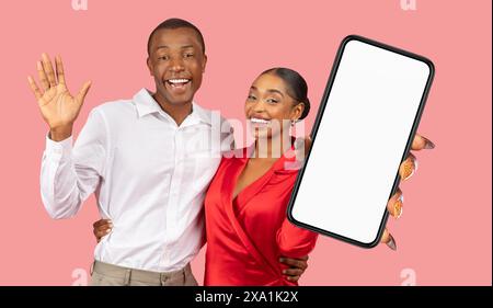 Glückliches Paar, Das Smartphone Mit Leerem Bildschirm Hält, Rosa Hintergrund Stockfoto