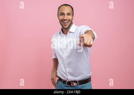 Überglückter Mann in weißem Hemd, der mit dem Finger auf die Kamera zeigt Stockfoto