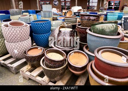 Stapel von verschiedenen bunten Pflanztöpfen zum Verkauf in einem lokalen Marktgarten. Stockfoto