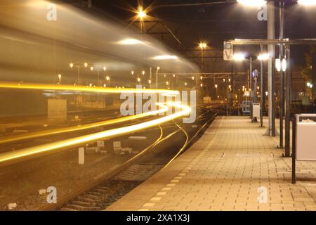 Der Zug fährt nachts durch beleuchtete Bahnhofsgleise Stockfoto