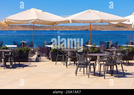 Restaurant im Freien mit Meerblick. Sommerterrasse mit Tischen und Stühlen unter weißen Sonnenschirmen Stockfoto