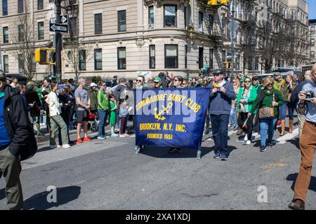 Eine Menschenmenge zieht durch die Straßen der Stadt, vorbei an Gebäuden. St. Patrick's Day in New York Stockfoto