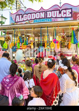 Festivalbesucher in traditioneller Kleidung in Feira de Abril in Sevilla, die während des einwöchigen Festivals bei einem süßen Händler anstehen Stockfoto