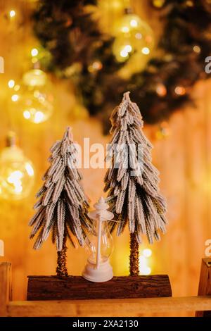 Drei kleine Bäume auf einem Tisch mit Kerzen und Weihnachtsbeleuchtung Stockfoto